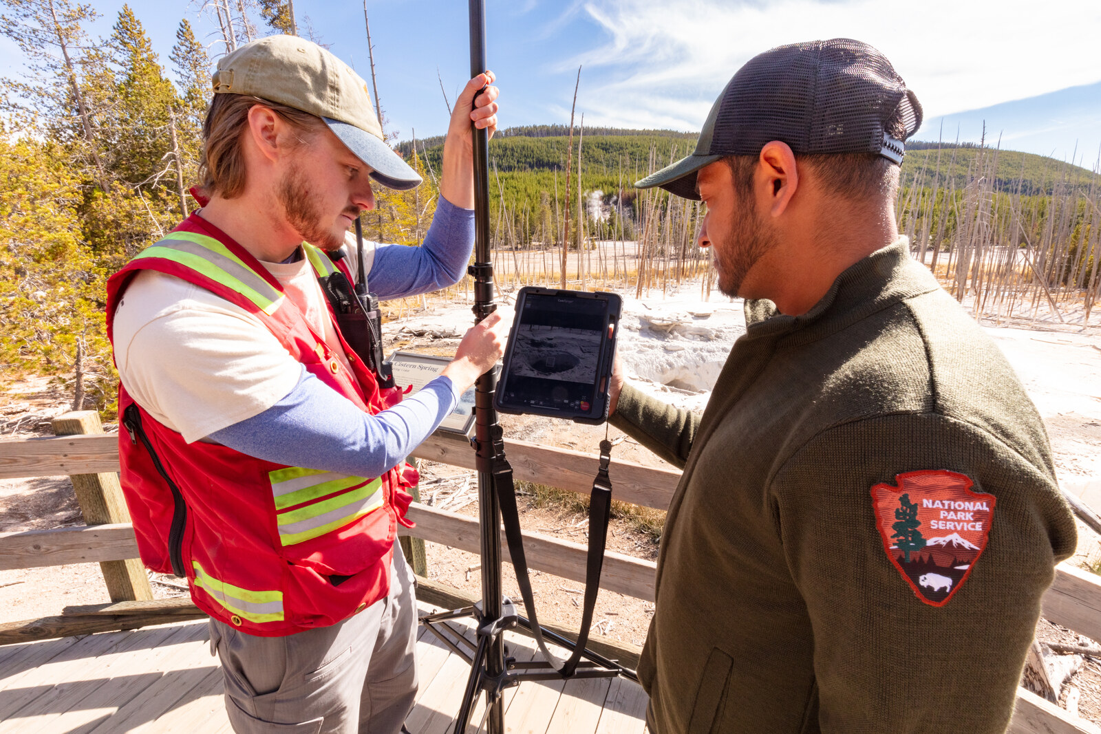 Two geoscientists collecting field data with survey equipment